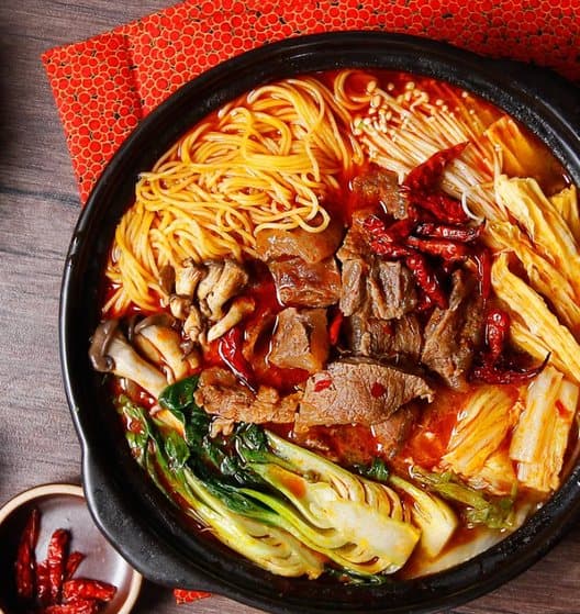 A bowl of malatang with beef, noodles and bok choy