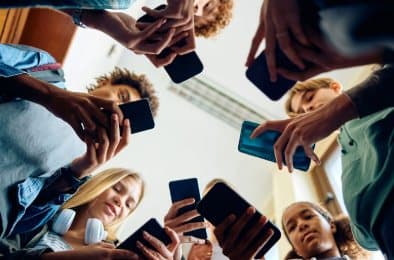 A circle of teenagers seen from below, each looking down at a phone
