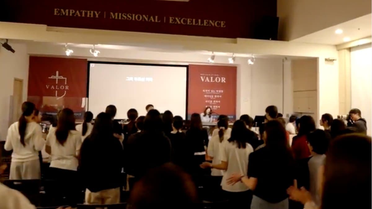 Students standing for worship in Mission Hall beneath the Empathy, Missional, Excellence banner